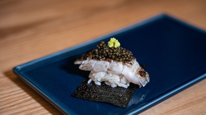 A delectable piece of squid nigiri topped with black caviar sits on a blue plate at Ogawa.
