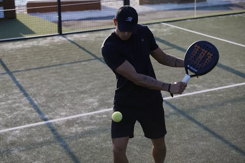 Image: A man playing hitting a ball with a padel racket