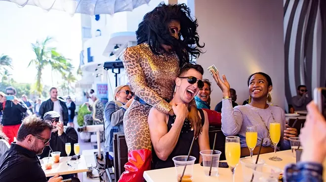 Drag queen hugs a guest from behind