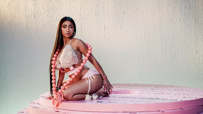 A woman is posing, sitting on a pink rug.