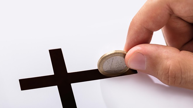 A coin being dropped into a crucifix slot.