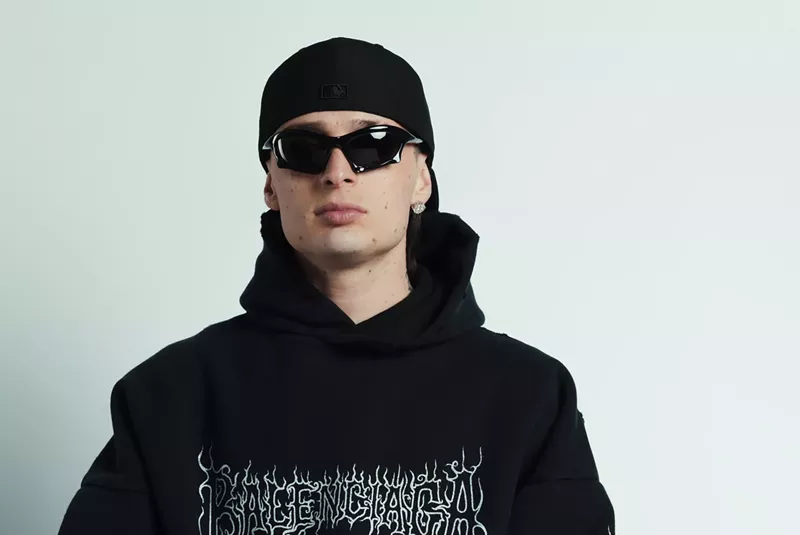Image: Peso Pluma wearing sunglasses and a black Balenciaga hoodie