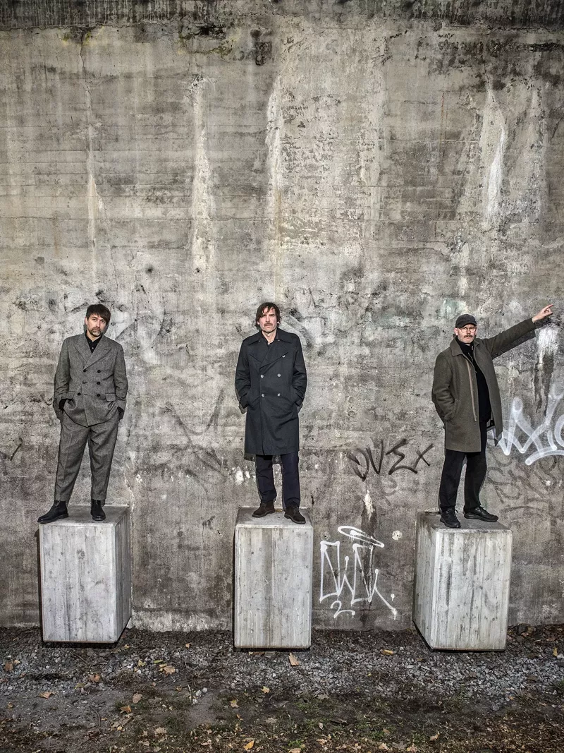Image: Three men stand on concrete blocks against a concrete backdrop. Very Swedish rock.