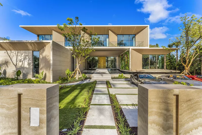 Image: Long entryway to a Miami Beach mansion with a modern, boxy look and tropical landscaping