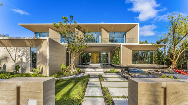 Long entryway to a Miami Beach mansion with a modern, boxy look and tropical landscaping