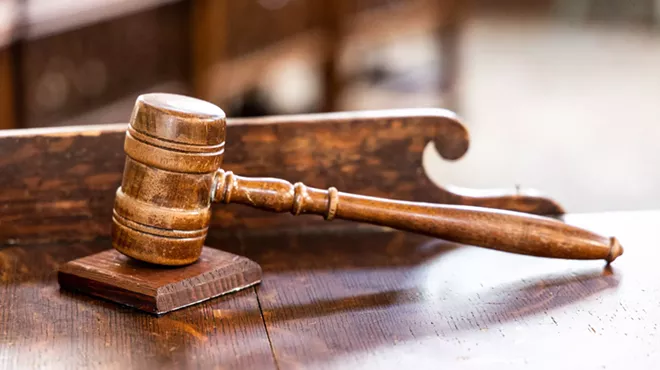 A judge's gavel sits on a wooden desk in a courtroom.