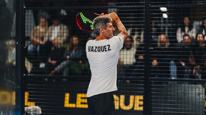 A man raising his racquet while playing padel on the court