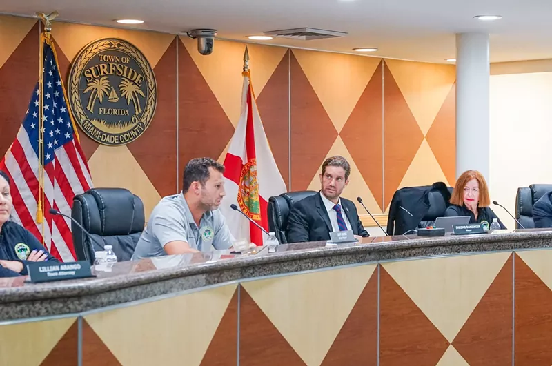 Image: Members of the Surfside town commission sit at the dais under a town crest