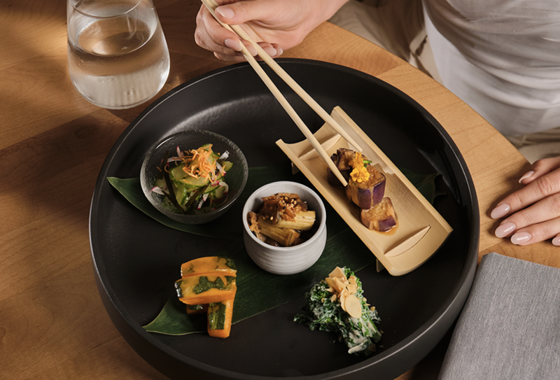 Image: hand eating sushi with chopsticks