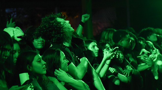Fans at the front row of a 100 gecs concert bathed in green light