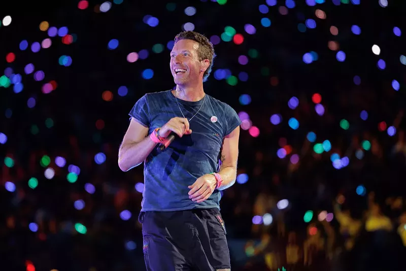 Image: Man with a microphone on stage surrounded by confetti