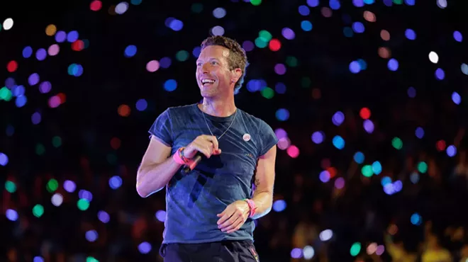Man with a microphone on stage surrounded by confetti