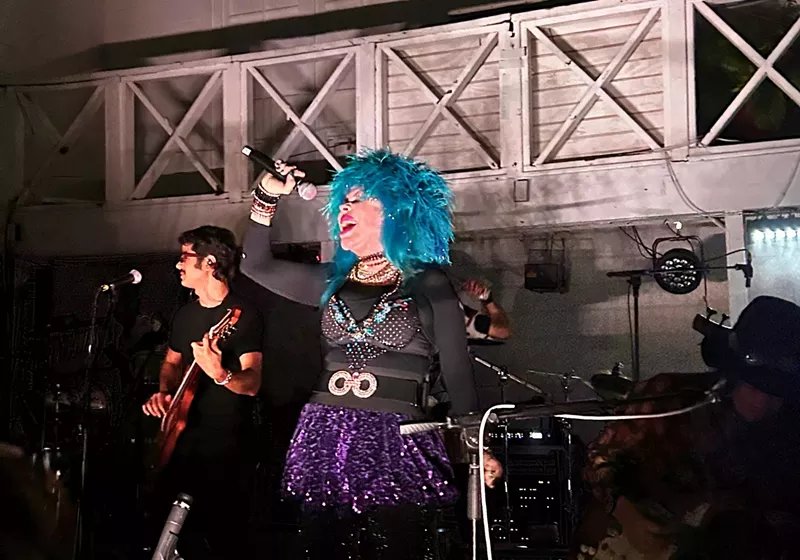 Image: A woman with blue hair is singing on stage.