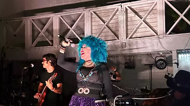 A woman with blue hair is singing on stage.