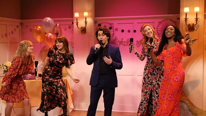 four women surround a man singing at a reception