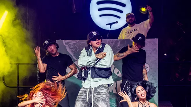 A man performing on stage with dancers and a Spotify logo in the back.