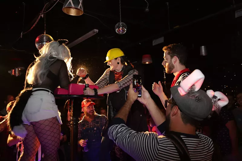 Image: Two women arm wrestling as the crowd cheers them on