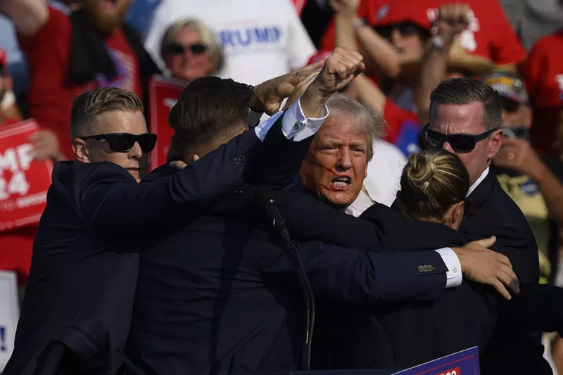 Image: Former president Donald Trump pumps his fist, his face covered in blood, as Secret Service agents whisk him away