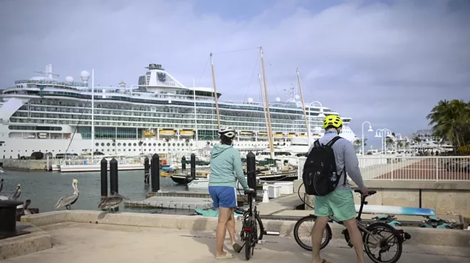 two cyclists stand with their bikes in front of a cruise shop