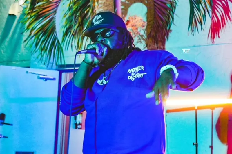 Image: Picture of a man wearing a hat and rapping while holding a microphone.