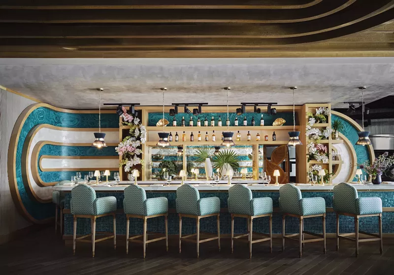 Image: a midcentury style bar with six plush chairs