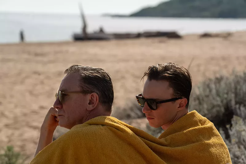 Image: two men sit side by side wearing a yellow blanket over their shoulders