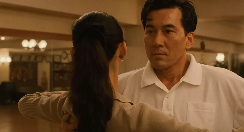 Image: film still from Masayuki Suo's Shall We Dance? shows a closeup of actor Kōji Yakusho speaking to a woman with her back to the viewer