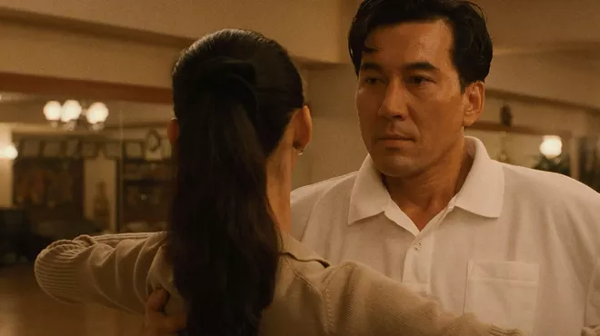 film still from Masayuki Suo's Shall We Dance? shows a closeup of actor Kōji Yakusho speaking to a woman with her back to the viewer