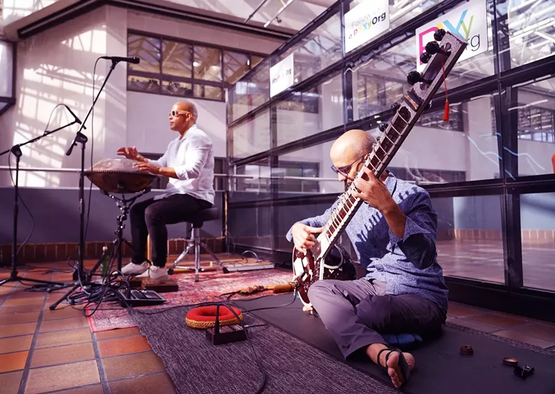 Image: two musicians play a sitar and a percussion instrument at a Miami train stattion