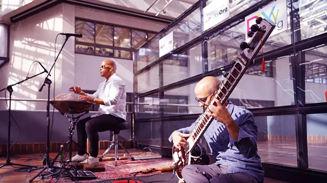 two musicians play a sitar and a percussion instrument at a Miami train stattion