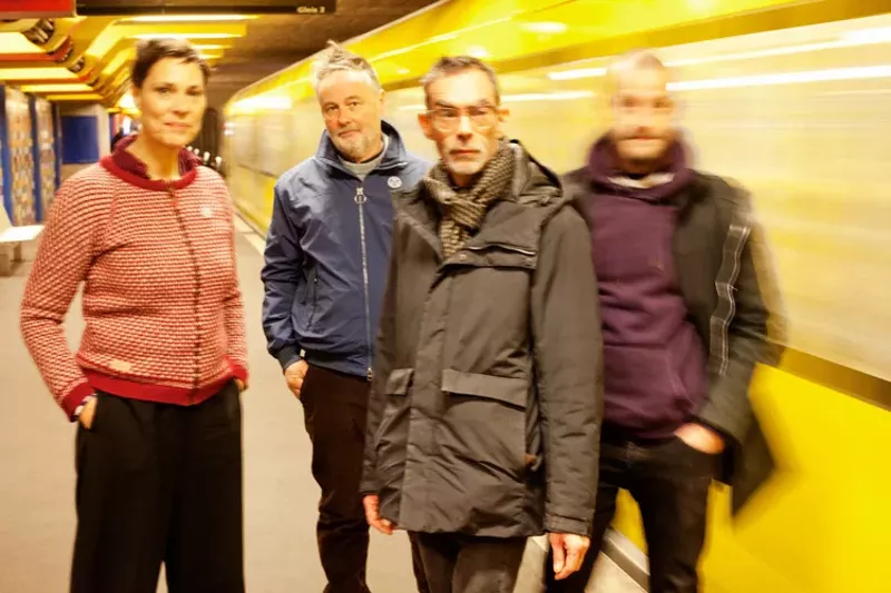 Image: Picture of a four-piece band posing by a subway.