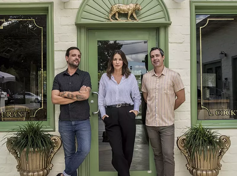 Image: Three people outside of a light green building and light green door