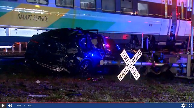 A mangled car in front of a Brightline train after the train collided with a car carrier