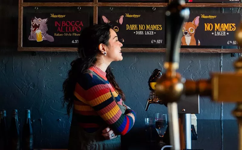 Image: a woman in a striped sweater standing next to a beer tap