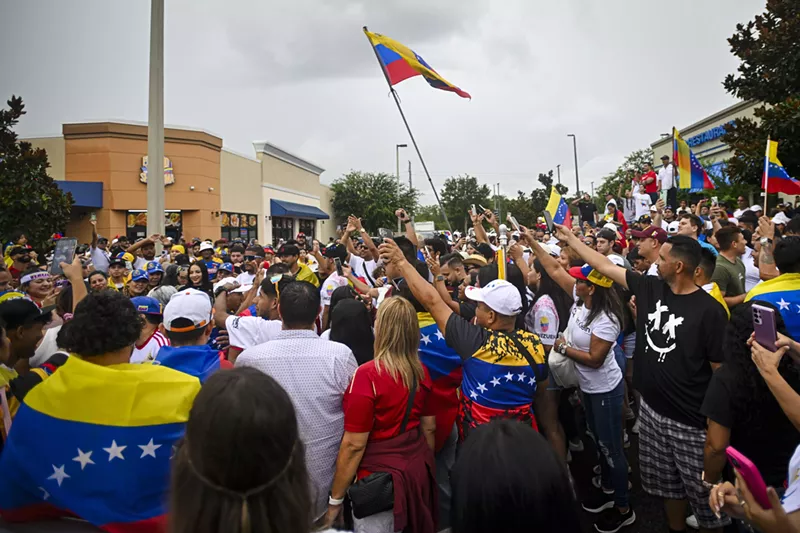 Image: A crowd packs together on an Orlando street, waving Venezuelan flags