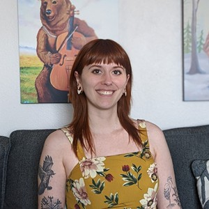 Woman smiling with long red hair and bangs