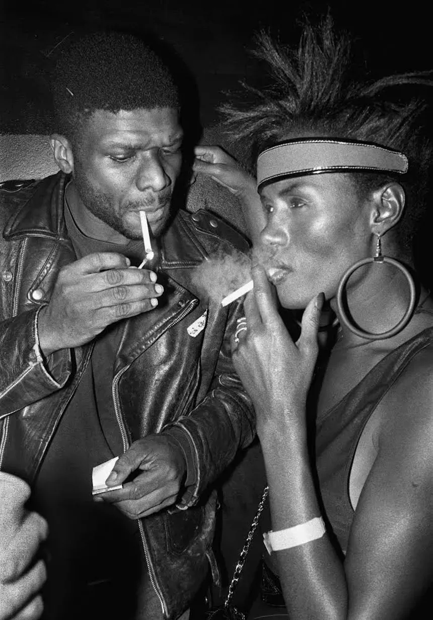 Larry Levan and Grace Jones smoking cigarettes at the Sound Factory in New York City in 1990.