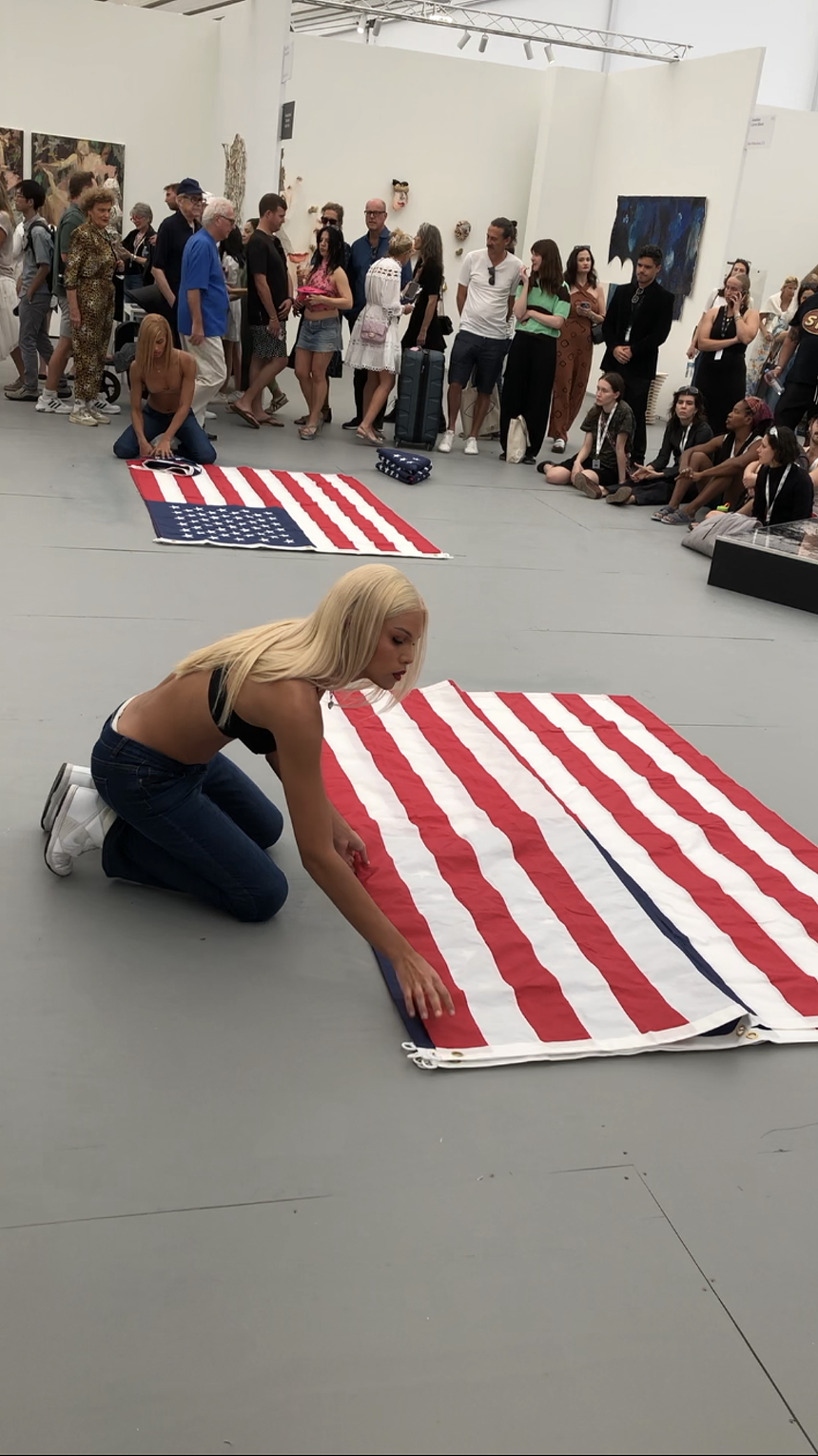 Two transgender women fold American flags as part of the performance art of Ms. Z Tye at Untitled art fair in Miami Beach