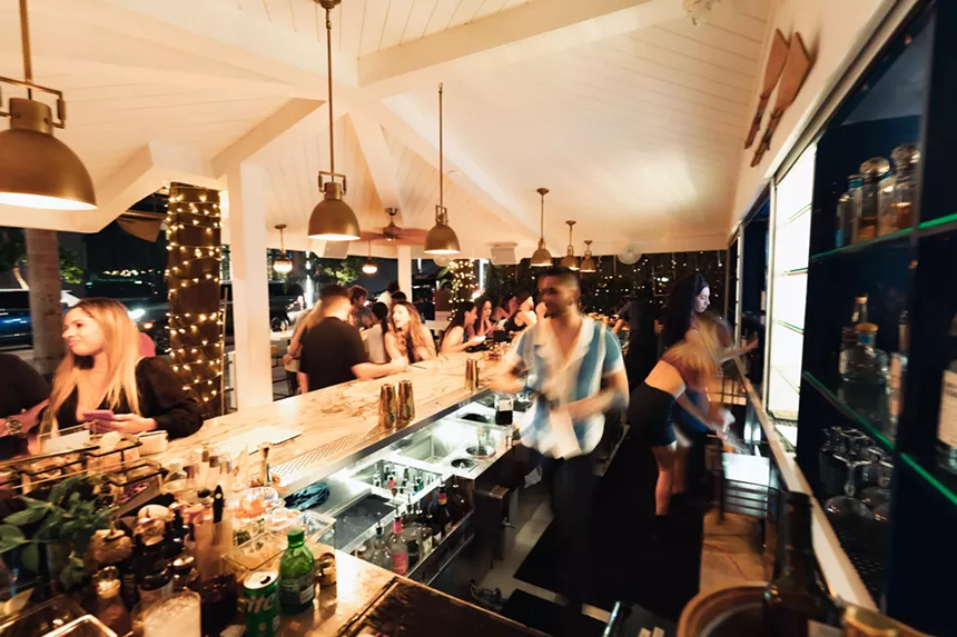 The bar at One K Raw filled with guests at night ordering drinks