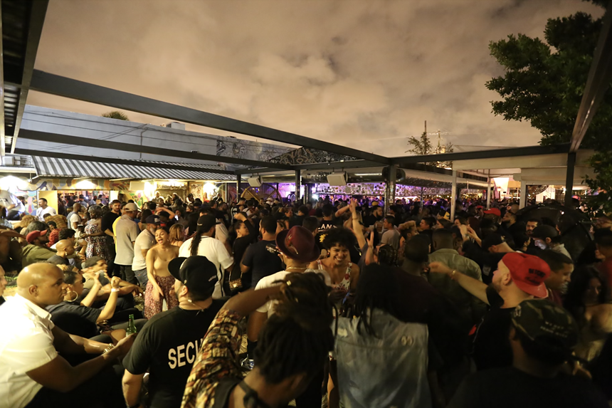 Wood Tavern in Wynwood is pictured with people at nighttime.