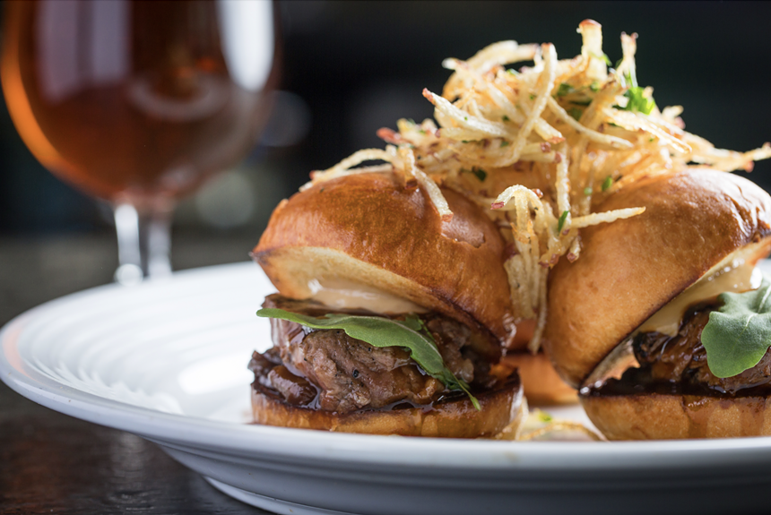 A tenderloin burger is surrounded by fries at Pinstripes in Aventura