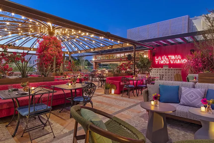 A pink neon sign is seen on the rooftop of Serena