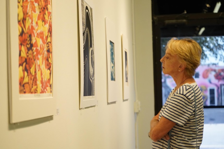 A woman looks at the art at the Florida Printmakers Society's 2023 Biennial Competition exhibition