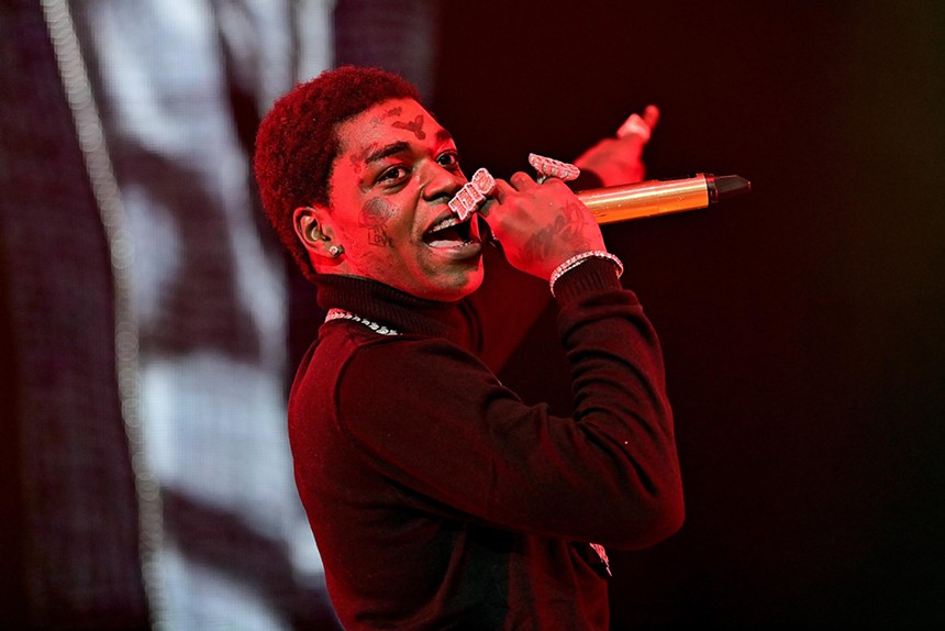 Rapper Kodak Black raps into a microphone on stage