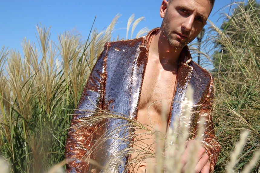 Jake Resnicow standing in a field in a gold-sequined jacket