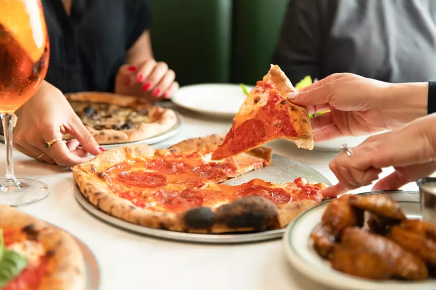 A hand grabs a slice of pizza