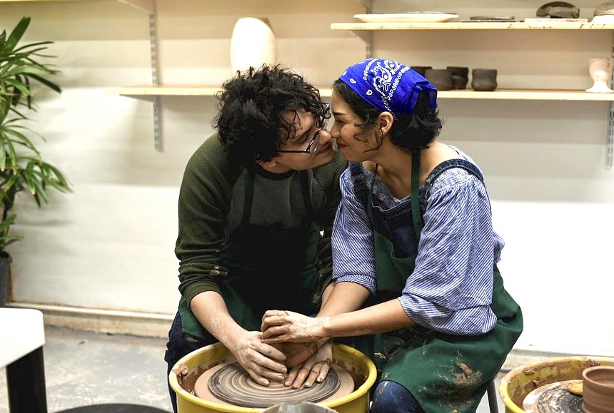 A couple kisses while making pottery