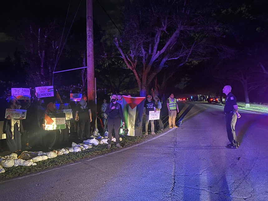 Protesters holding signs on a residential street on a dark night