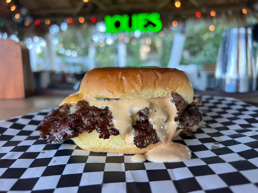 A juicy smash burger with sauce spilling over