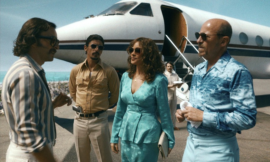 Still from Griselda in which Sofía Vergara and four men stand on a seaside runway with a private jet behind them